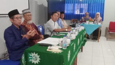 Sejumlah pengurus organisasi mengenakan peci dan pakaian formal duduk mengikuti jalannya rapat di meja ber-taplak hijau berlogo