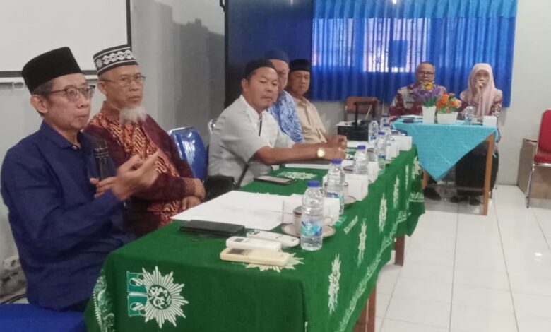 Sejumlah pengurus organisasi mengenakan peci dan pakaian formal duduk mengikuti jalannya rapat di meja ber-taplak hijau berlogo