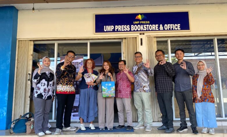 Rombongan tamu berpose bersama sambil menunjukkan gestur tangan di depan papan nama UMP Press Bookstore & Office.