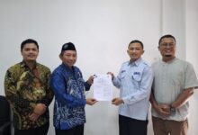 Empat orang pria berpose bersama sambil memegang dokumen kerja sama, salah satunya mengenakan seragam biru berlogo UMS.