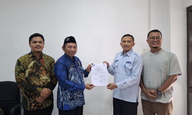 Empat orang pria berpose bersama sambil memegang dokumen kerja sama, salah satunya mengenakan seragam biru berlogo UMS.