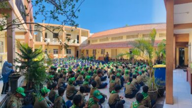 Ratusan siswa berseragam pramuka duduk rapi di halaman sekolah mendengarkan pengarahan.