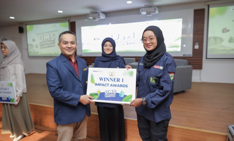 Seorang pria mengenakan jas blazer biru menyerahkan plakat penghargaan bertuliskan Winner 1 Impact Awards kepada mahasiswi berhijab di atas panggung.
