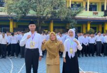 Kepala sekolah berfoto bersama dua perwakilan siswa baru peserta MPLS SMA Muhammadiyah 1 Temanggung 2026 di halaman sekolah.