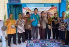 Sembilan pria berpose bersama sambil memamerkan bibit kelapa kopyor yang telah bertunas di depan banner program UMKM.