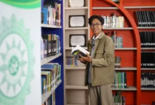 Hardika Dwi Hermawan Kabid Pengelolaan dan Layanan Digital UPT Perpustakaan UMS memegang buku di perpustakaan