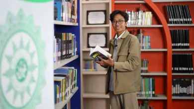 Hardika Dwi Hermawan Kabid Pengelolaan dan Layanan Digital UPT Perpustakaan UMS memegang buku di perpustakaan