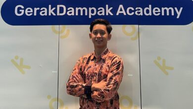 Abi Umaroh, mahasiswa Magister Ilmu Hukum UMS, berdiri mengenakan kemeja batik lengan panjang di depan spanduk GerakDampak Academy.