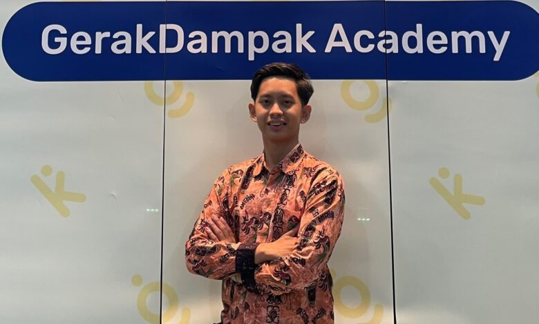 Abi Umaroh, mahasiswa Magister Ilmu Hukum UMS, berdiri mengenakan kemeja batik lengan panjang di depan spanduk GerakDampak Academy.