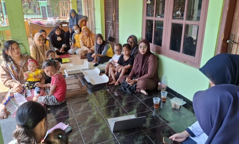 Ibu-ibu dan balita di Posyandu Krajan Sukoharjo mendengarkan penyuluhan mahasiswa fisioterapi UMS tentang bahaya posisi duduk W pada anak, menggunakan laptop di teras rumah.