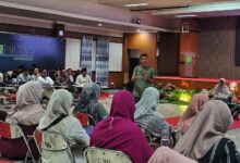 Ikhwanushoffa, Manajer Eksekutif PWM Jawa Tengah, memberikan paparan materi dalam Baitul Arqom Tendik di aula Universitas Muhammadiyah Gombong (Unimugo), Kebumen. Foto diambil dari sudut audiens wanita berhijab.