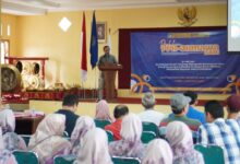 Wakil Rektor III UMP, Drs. Ikhsan Mujahid, M.Si., memberikan sambutan di podium pada acara Grand Launching program SI-PINTAR di hadapan audiens warga Desa Purbadana dan sivitas akademika UMP.