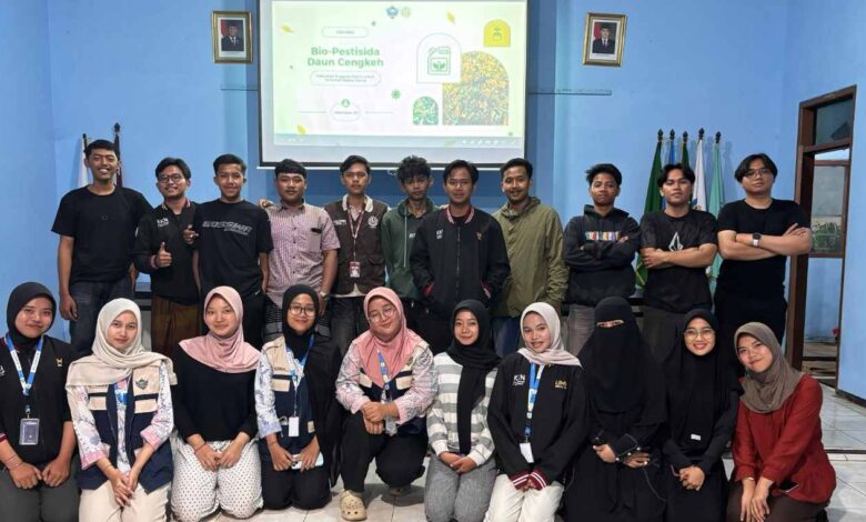 Tim Mahasiswa KKN MAs Kelompok 39 Malang bersama pemuda Karang Taruna Dusun Codo, Wagir, berfoto bersama setelah sesi presentasi pembuatan pestisida nabati daun cengkeh di dalam ruangan, dengan latar belakang layar proyeksi yang menyala.