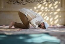 Seorang pria sedang sujud saat melaksanakan sholat di dalam masjid.