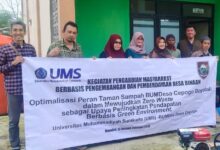 Tim pengabdian UMS dan warga membentangkan spanduk program inovasi pengelolaan sampah untuk mewujudkan ekonomi sirkular di BUMDesa Cepogo Boyolali.