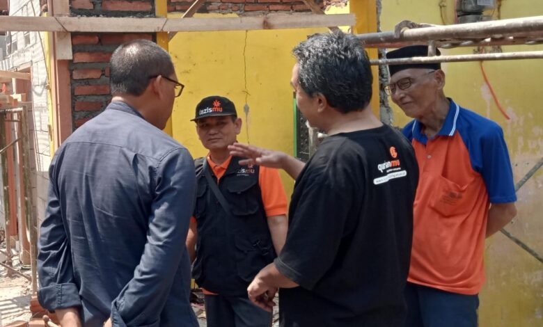 Ketua PCM Kedungwuni Mustami'an berbincang dengan relawan dan Mbah Danali di lokasi program Bedah Rumah LAZISMU Pekalongan.
