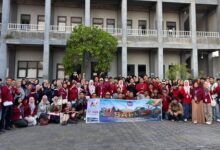 Peserta kunjungan industri lintas prodi TMU foto bersama membawa spanduk keberangkatan ke Bali di Kampus 2 TMU Tegal.