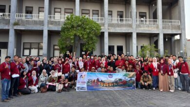 Peserta kunjungan industri lintas prodi TMU foto bersama membawa spanduk keberangkatan ke Bali di Kampus 2 TMU Tegal.