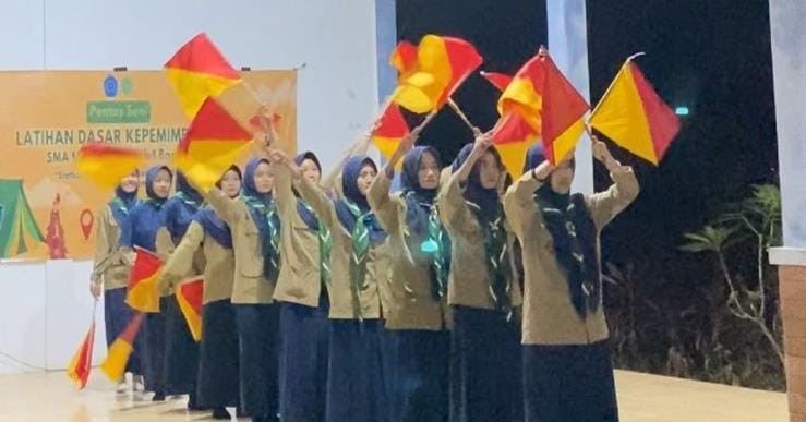 Siswa berhijab menampilkan atraksi bendera semapur saat LDK SMA Muhammadiyah 1 Bangsri di Gua Sakti Plajan.