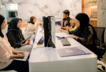 Petugas pelayanan akademik berhijab sedang melayani registrasi mahasiswa baru di loket informasi UMS yang modern.