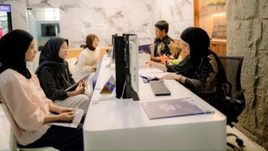 Petugas pelayanan akademik berhijab sedang melayani registrasi mahasiswa baru di loket informasi UMS yang modern.