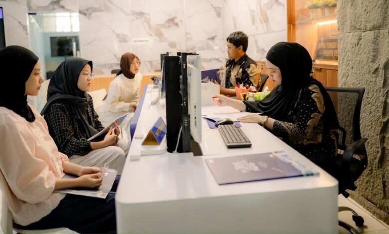 Petugas pelayanan akademik berhijab sedang melayani registrasi mahasiswa baru di loket informasi UMS yang modern.