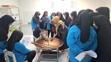 Tim pengabdian UMS mendampingi anggota KWT Sumber Rejeki menyaring cairan herbal dalam wajan besar untuk pembuatan produk olahan rempah Boyolali.