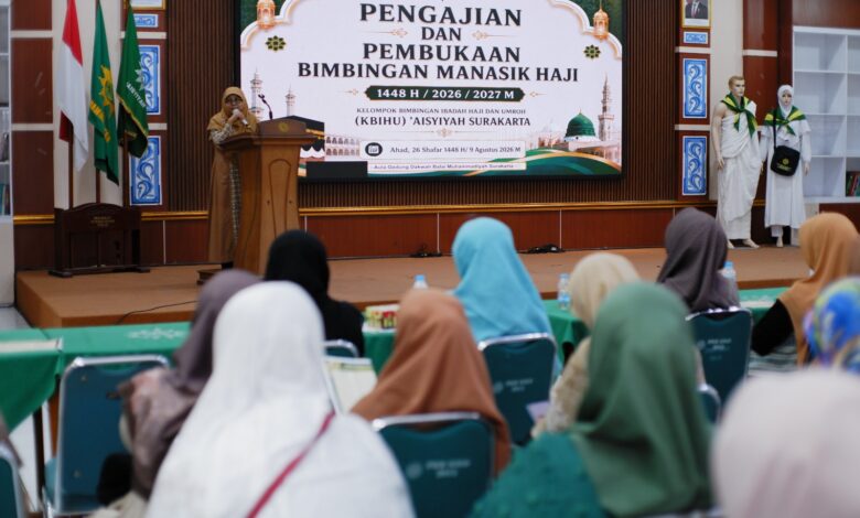 Suasana pembukaan manasik haji 2027 KBIHU Aisyiyah Surakarta, seorang pembicara wanita di podium menghadap peserta di aula.