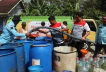 Petugas Pertamina Patra Niaga dan Lazismu menyalurkan bantuan air bersih di Cilacap ke dalam drum dan galon warga.