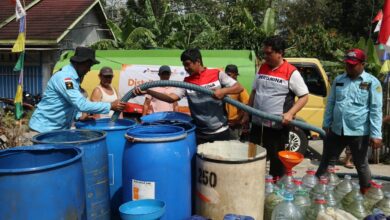 Petugas Pertamina Patra Niaga dan Lazismu menyalurkan bantuan air bersih di Cilacap ke dalam drum dan galon warga.