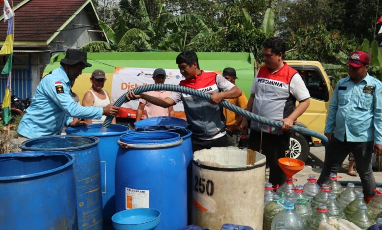 Petugas Pertamina Patra Niaga dan Lazismu menyalurkan bantuan air bersih di Cilacap ke dalam drum dan galon warga.