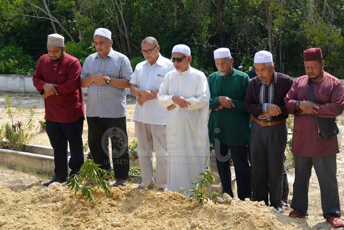 Sekelompok Muslim melaksanakan salat jenazah di dekat makam setelah proses pemakaman.
