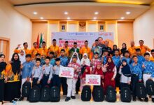 Puluhan pelajar Muhammadiyah berfoto bersama pengurus Lazismu Jepara sambil membawa tas ransel dan papan simbolis penerimaan beasiswa pendidikan Mentari di Aula PPNI.