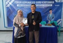 Dua perwakilan peserta pelatihan branding sekolah Muhammadiyah Dukuhturi menunjukkan buku panduan di depan spanduk acara.