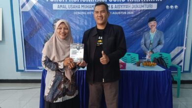 Dua perwakilan peserta pelatihan branding sekolah Muhammadiyah Dukuhturi menunjukkan buku panduan di depan spanduk acara.