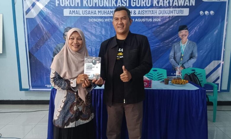 Dua perwakilan peserta pelatihan branding sekolah Muhammadiyah Dukuhturi menunjukkan buku panduan di depan spanduk acara.