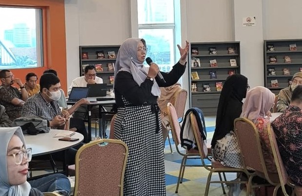 Kepala Perpustakaan UMS, Maria Husnun Nisa, berdiri memegang mikrofon saat mempresentasikan inovasi perpustakaan digital Program IMAM di hadapan akademisi University Malaya, Malaysia.