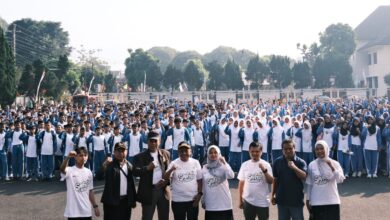 Ribuan pelajar Muhammadiyah Wonosobo mengenakan seragam biru-putih dan jilbab memadati Halaman Sasana Adipura, berpose semangat dengan kepalan tangan. Di latar depan, tamu VIP mengenakan kaus acara berlogo SMUFest 2026 Wonosobo. Latar belakang menampilkan Alun-Alun Wonosobo. Gambar mendokumentasikan puncak Fortasi 2026.