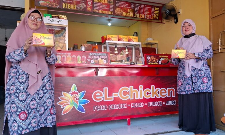 Dua pengelola berpose di depan gerai resmi El Chicken Pekalongan sambil memegang kemasan produk ayam andalan.