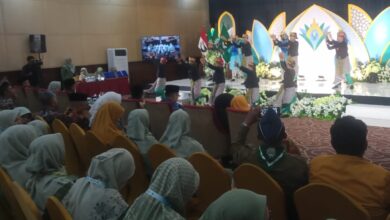 Penari tradisional dengan kostum hitam-emas tampil di atas panggung di hadapan ratusan anggota Nasyiatul Aisyiyah yang berkerudung seragam hijau muda di sebuah aula konvensi hotel saat acara formal, dengan latar belakang dekorasi panggung panel teal-emas dan bunga putih serta sebuah gong besar.