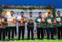Pemenang penghargaan Cabang dan Ranting Muhammadiyah (LPCRPM) foto bersama di atas panggung memegang plakat dan sertifikat penghargaan.