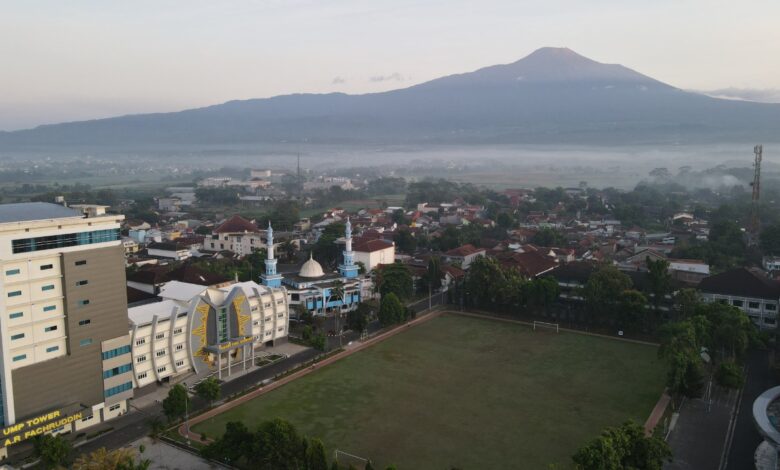 Pemandangan udara Kampus Utama UMP Purwokerto dengan latar belakang Gunung Slamet di pagi hari, menunjukkan fasilitas modern yang mendukung riset dan pencapaian peringkat SINTA nasional.
