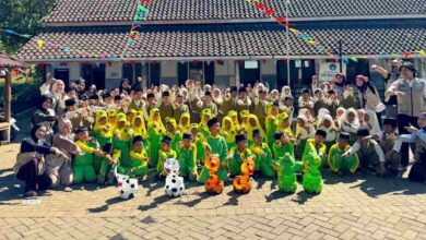 Siswa MI Wahid Hasyim dan mahasiswa KKNMAs Kelompok 12 foto bersama memamerkan kreasi botol bekas media tanam berbentuk karakter hewan.