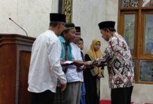 Pria berbatik memberikan santunan kepada warga dalam acara Peringatan Maulid Nabi di Masjid Nurul ‘Aini, Karanggeneng, Boyolali, disaksikan oleh tokoh PRM Karanggeneng dan Lazismu.
