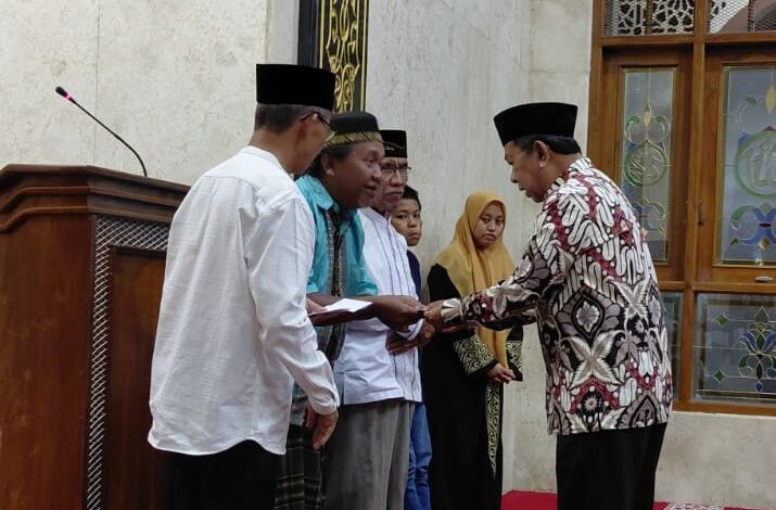 Pria berbatik memberikan santunan kepada warga dalam acara Peringatan Maulid Nabi di Masjid Nurul ‘Aini, Karanggeneng, Boyolali, disaksikan oleh tokoh PRM Karanggeneng dan Lazismu.