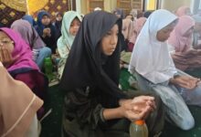 Sekelompok siswi MIM Kauman berkerudung duduk khusyuk di masjid sambil mengangkat tangan berdoa saat acara kajian Maulid Nabi 1448 H.