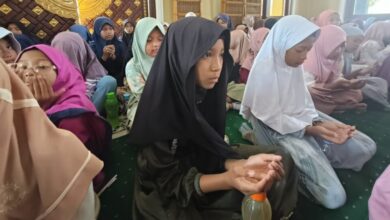 Sekelompok siswi MIM Kauman berkerudung duduk khusyuk di masjid sambil mengangkat tangan berdoa saat acara kajian Maulid Nabi 1448 H.