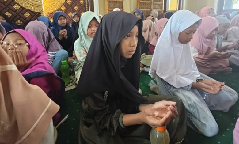 Sekelompok siswi MIM Kauman berkerudung duduk khusyuk di masjid sambil mengangkat tangan berdoa saat acara kajian Maulid Nabi 1448 H.