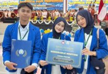 Tim mahasiswa Farmasi UMP pemenang Honorable Mention dalam lomba poster nasional Expanding Science Defense ke-4 di Universitas Pertahanan, memegang sertifikat penghargaan dan map di atas panggung dengan latar belakang spanduk acara dan kelompok paduan suara.