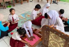 Siswa anak disleksia SDN Nayu Barat 1 mendampingi mahasiswa UMS belajar menulis huruf menggunakan media pasir merah muda dan plastisin.